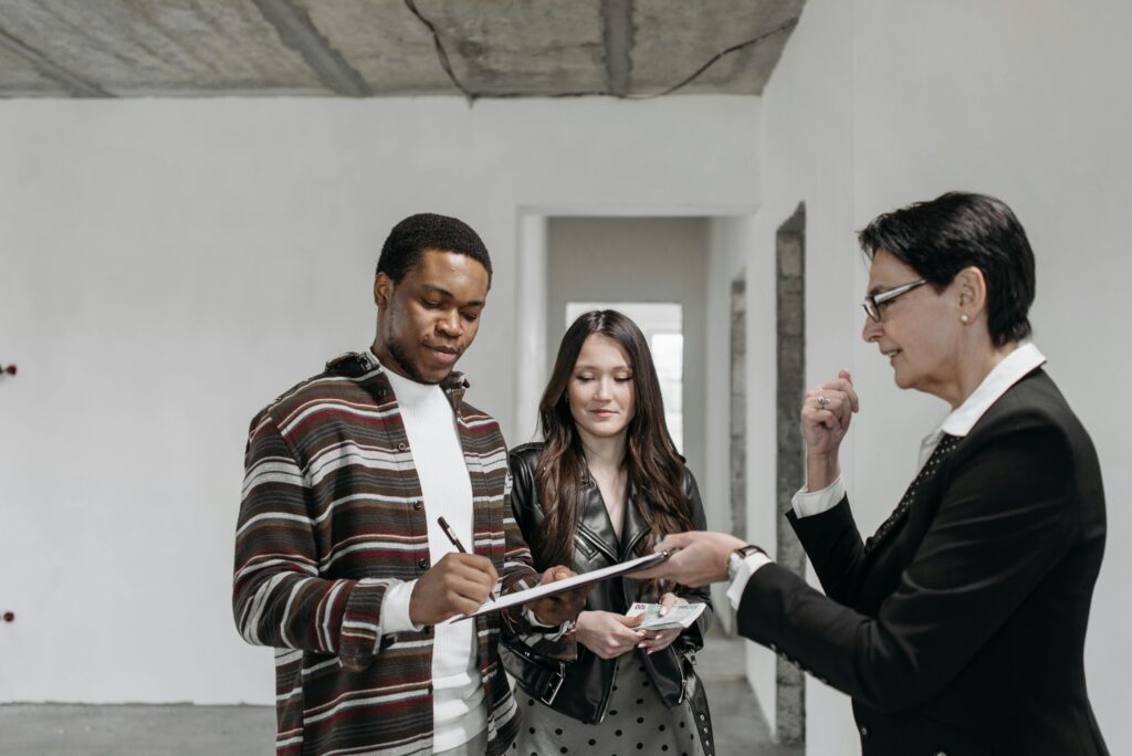 pexels-photo-7937708-7937708 A diverse couple signing documents with a realtor in a new home setting.
